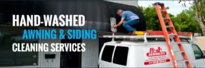 Mike Jackson is standing on the top of his customized company van to clean a commercial awning by hand.